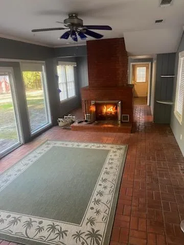 a view of an empty room with window and chandelier fan