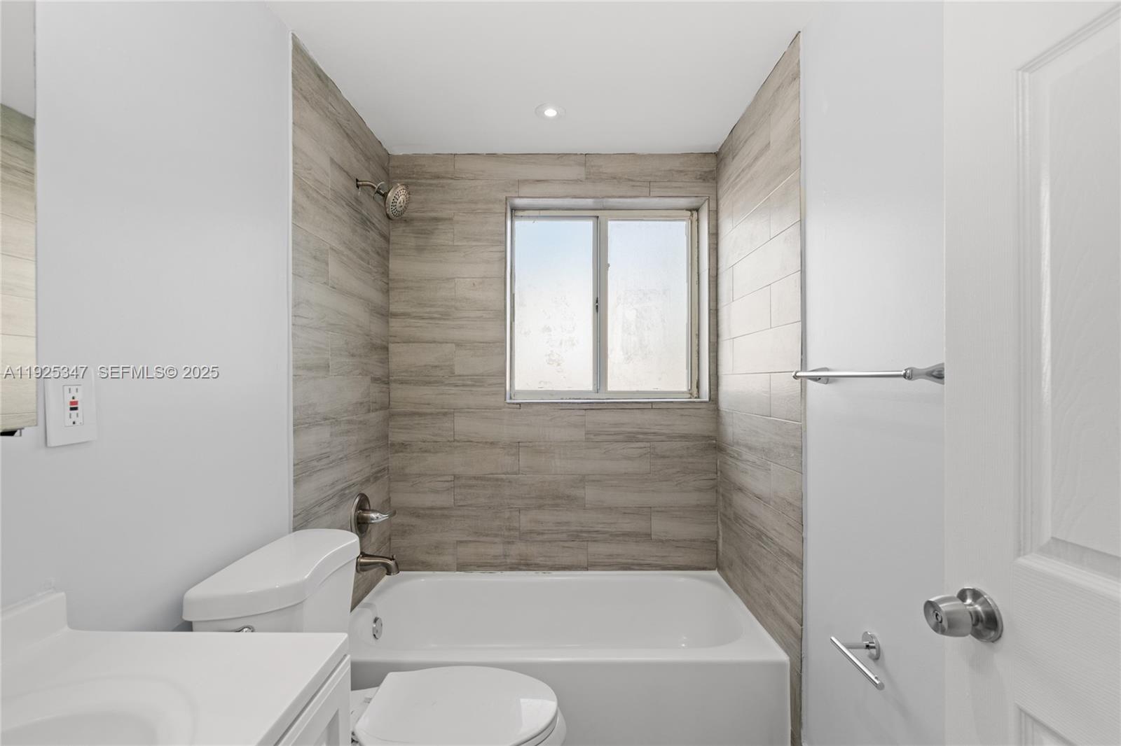 980 Northeast 170th Street, Unit 118 North Miami Beach, FL 33162 - Photo 12 of 32 a bathroom with a granite countertop bathtub toilet and shower