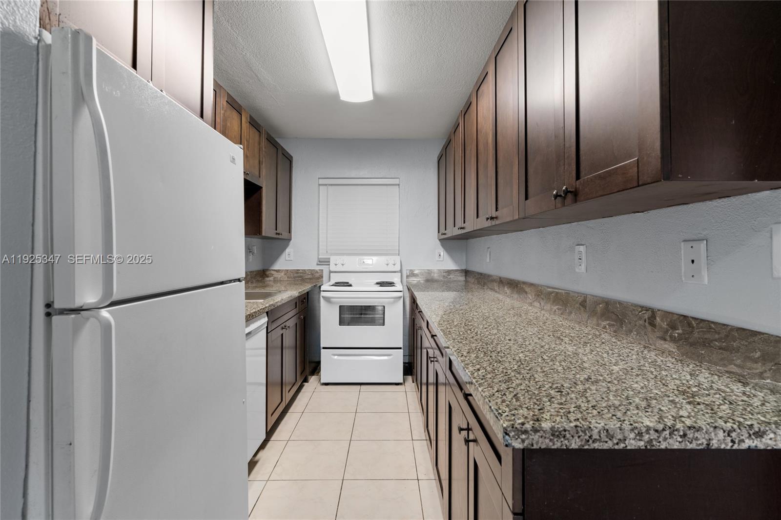 980 Northeast 170th Street, Unit 118 North Miami Beach, FL 33162 - Photo 3 of 32 a kitchen with a refrigerator sink and cabinets