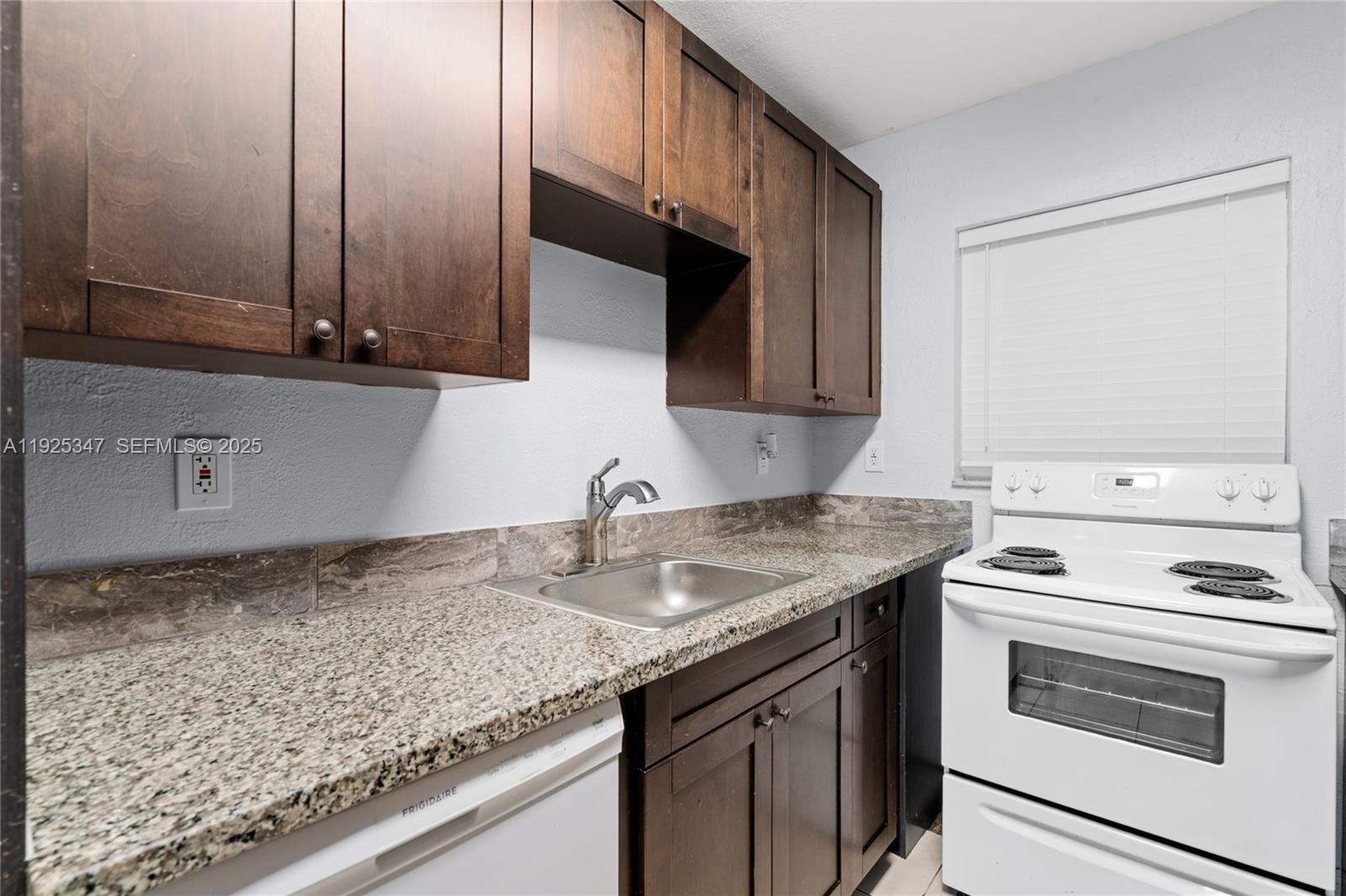 980 Northeast 170th Street, Unit 118 North Miami Beach, FL 33162 - Photo 5 of 32 a kitchen with stainless steel appliances granite countertop a sink stove and cabinets