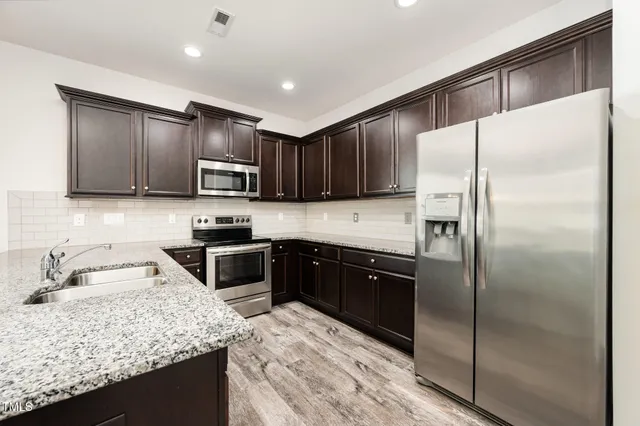 a kitchen with stainless steel appliances granite countertop a refrigerator a stove a sink and a microwave