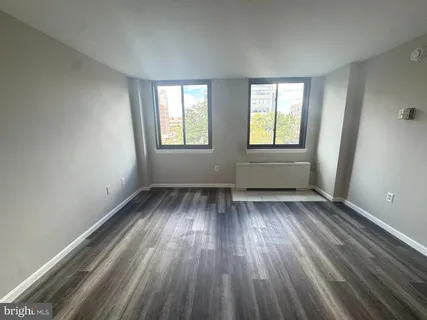an empty room with wooden floor and windows