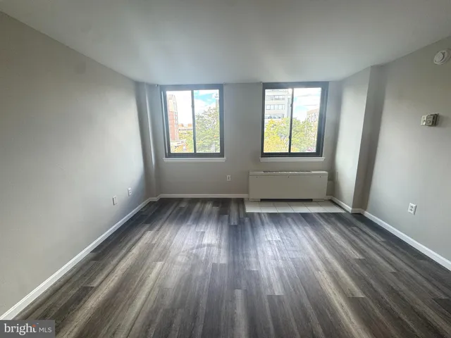 an empty room with wooden floor and windows