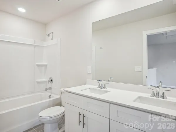a bathroom with a bathtub shower sink vanity mirror and toilet