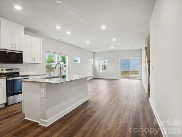a open kitchen with kitchen island a sink dishwasher stove and wooden floor