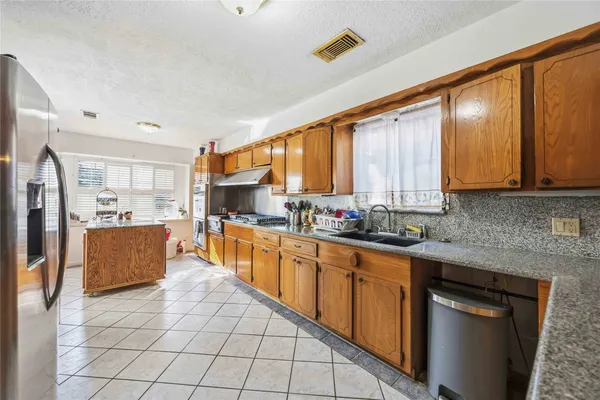 a large kitchen with stainless steel appliances kitchen island granite countertop a stove top oven a sink dishwasher a dining table and chairs with wooden floor