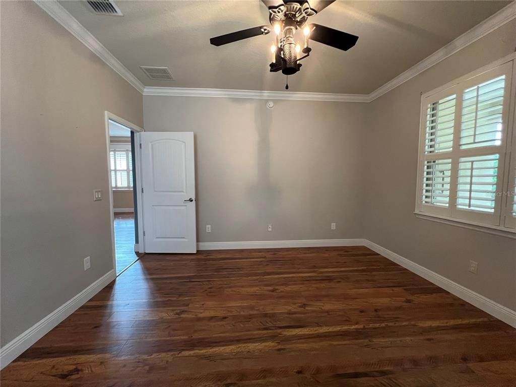 9515 Southwest 76th Street Ocala, FL 34481 - Photo 17 of 55 an empty room with wooden floor chandelier fan and windows