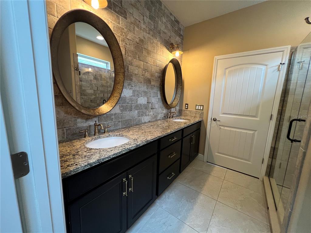 9515 Southwest 76th Street Ocala, FL 34481 - Photo 27 of 55 a bathroom with a granite countertop sink a mirror and a shower