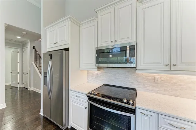 a kitchen with stainless steel appliances a refrigerator a stove and white cabinets