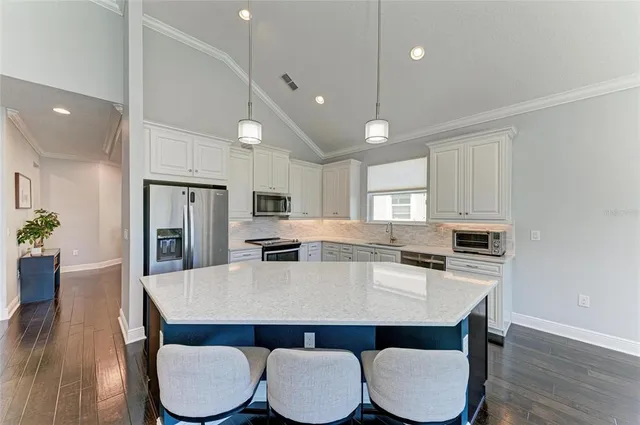 a kitchen with stainless steel appliances a dining table chairs and wooden floor