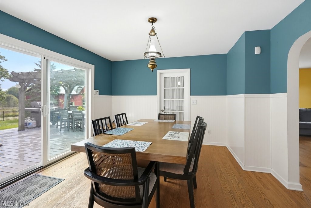 149 North Medina Line Road Akron, OH 44333 - Photo 10 of 42 Wood-finish flooring, half-wall wainscoting, sliding glass door to exterior deck, arched doorway, and overhead lighting fixture