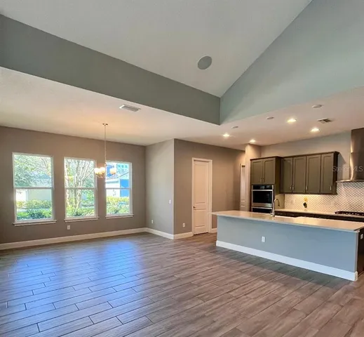 a large kitchen with stainless steel appliances a large counter top a stove and a refrigerator