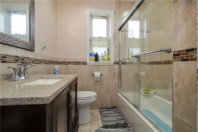 a bathroom with a granite countertop sink a toilet a mirror and shower