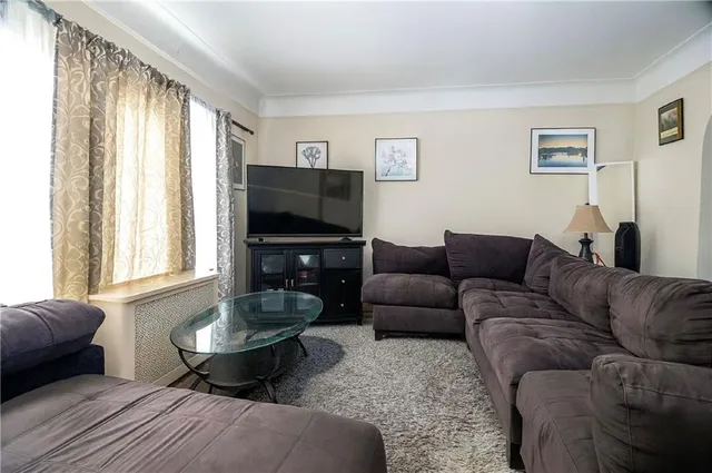 a living room with furniture a flat screen tv and a window