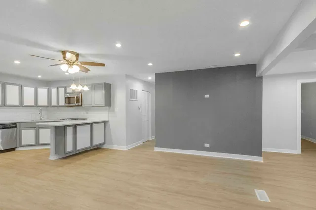 a view of an empty room with kitchen and window
