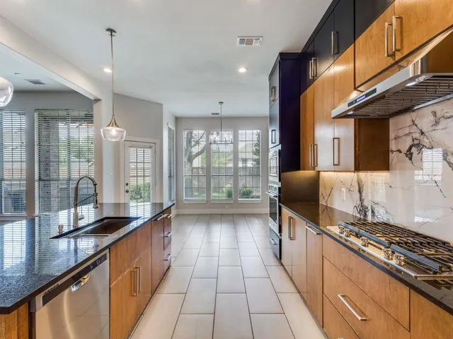 a large kitchen with granite countertop a large counter top space a sink stainless steel appliances and cabinets