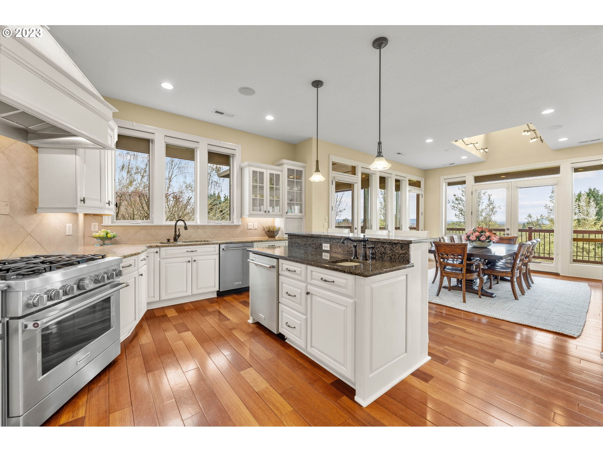 6405 Northwest 202nd Circle Ridgefield, WA 98642 - Photo 21 of 45 a kitchen with stainless steel appliances granite countertop a stove top oven a sink dishwasher a dining table and chairs with wooden floor