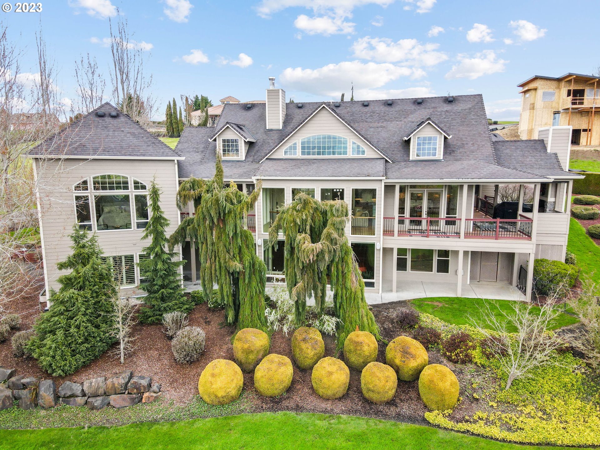 6405 Northwest 202nd Circle Ridgefield, WA 98642 - Photo 44 of 45 a view of a white house with large windows and a yard with plants