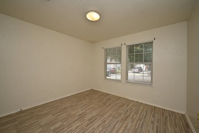 an empty room with wooden floor and windows