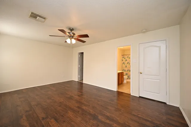 an empty room with wooden floor and ceiling fan