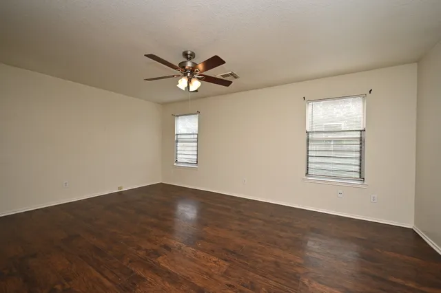 an empty room with wooden floor and windows