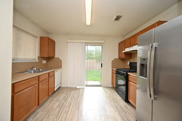 a kitchen with granite countertop a refrigerator stove top oven and sink