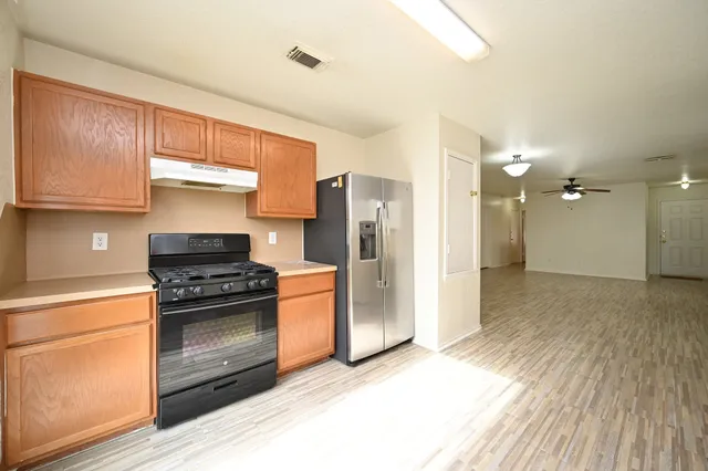 a kitchen with a refrigerator stove and wooden cabinets