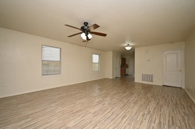 a view of empty room with wooden floor and ceiling fan