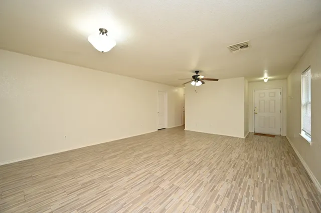 an empty room with wooden floor and windows