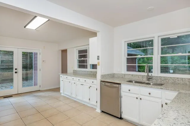 a kitchen with granite countertop a sink window and white cabinets