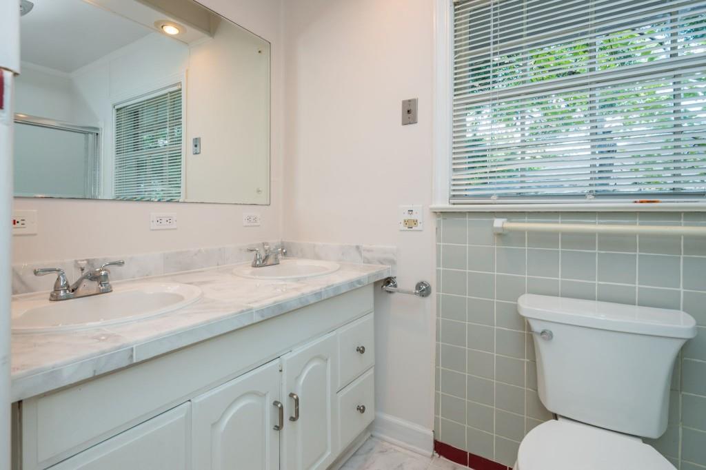 1392 Lively Ridge Road Northeast Atlanta, GA 30329 - Photo 30 of 42 a bathroom with a granite countertop toilet a sink a mirror and a window