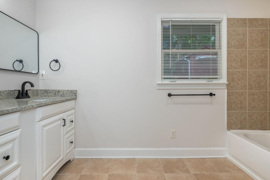 1392 Lively Ridge Road Northeast Atlanta, GA 30329 - Photo 36 of 42 a bathroom with a granite countertop sink a mirror and a bathtub