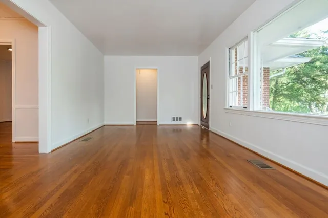 a view of an empty room with wooden floor and a window