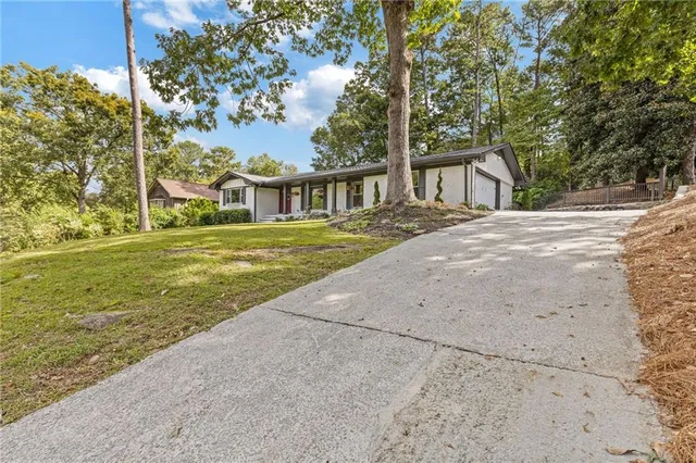 a front view of a house with a garden and trees