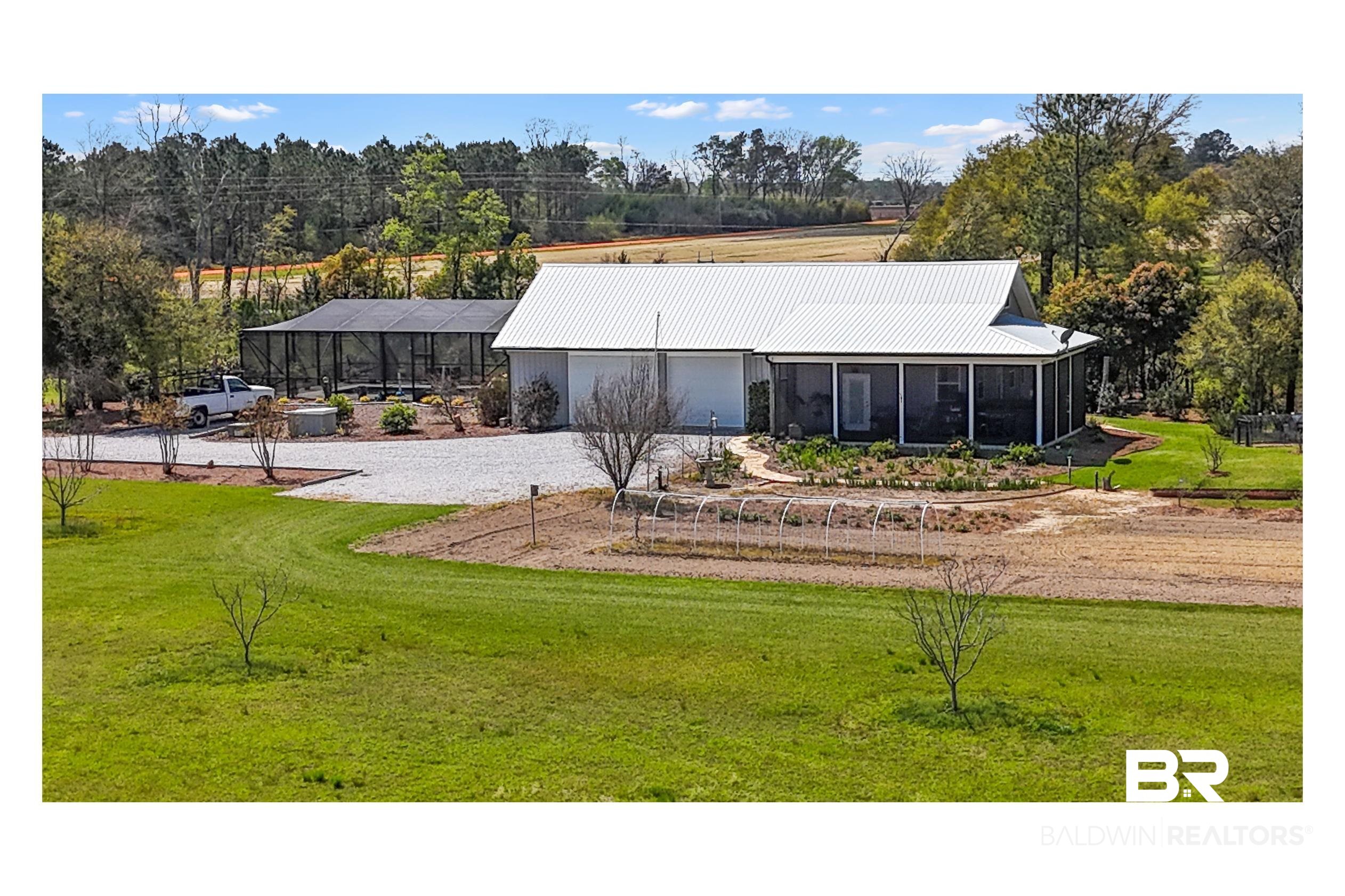26071 Woerner Road Elberta, AL 36530 - Photo 26 of 86 Exterior space with gravel driveway, an attached garage, a yard, and metal roof