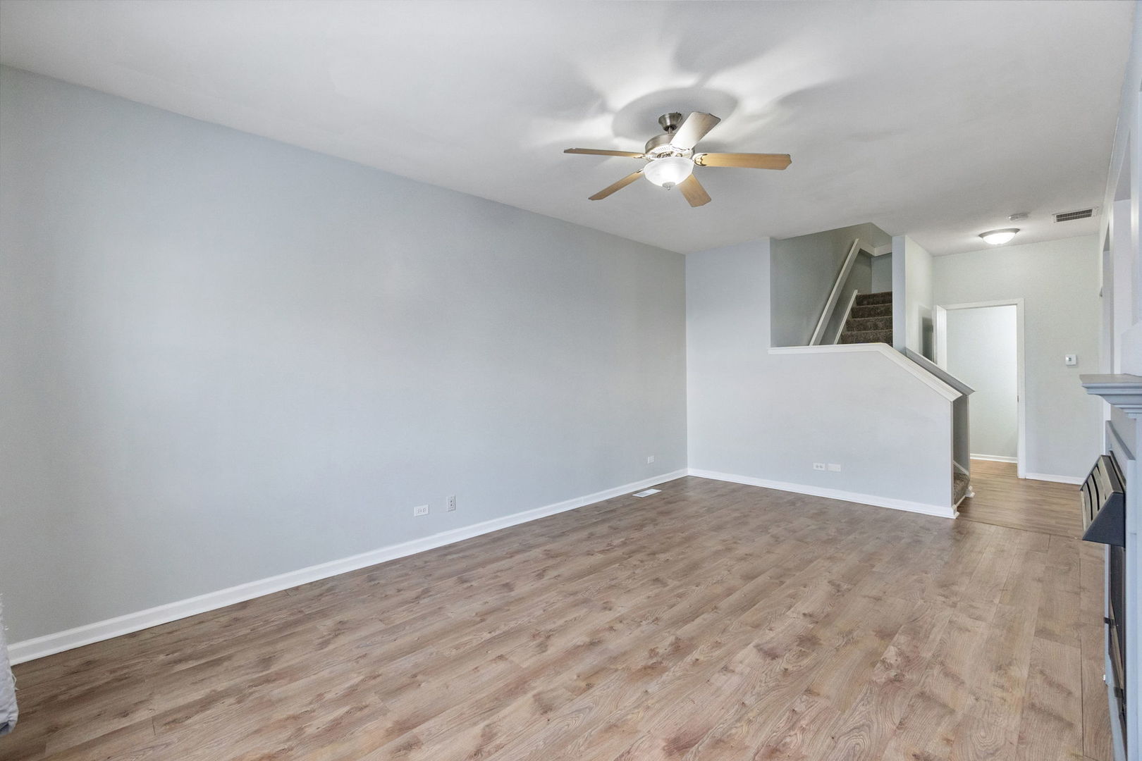 199 North Oakhurst Drive, Unit 199 Aurora, IL 60504 - Photo 5 of 25 a view of an empty room with wooden floor and a ceiling fan