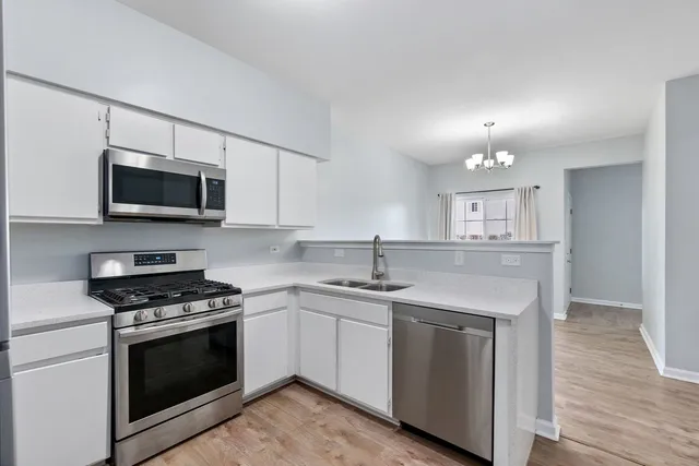 a kitchen with cabinets stainless steel appliances and wooden floor