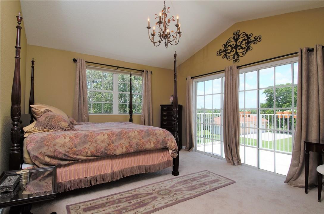 17401 Sunset Drive Southwest Ranches, FL 33331 - Photo 20 of 45 a spacious bedroom with a bed and a chandelier
