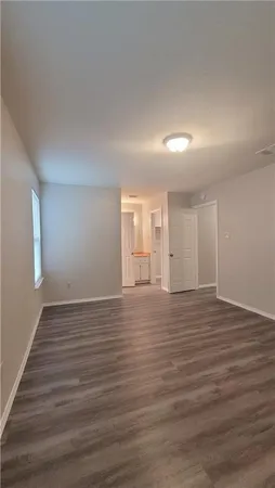 a view of an empty room with wooden floor and window