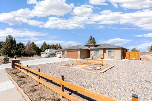 357 East Main Street Enterprise, UT 84725 - Photo 6 of 71 Prairie-style house featuring a fenced front yard, driveway, an attached garage, and stone siding
