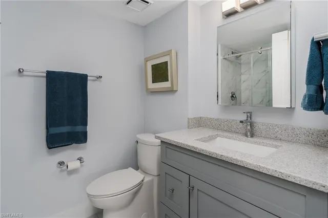 a bathroom with a granite countertop toilet sink and mirror