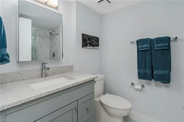 a bathroom with a granite countertop toilet sink and mirror
