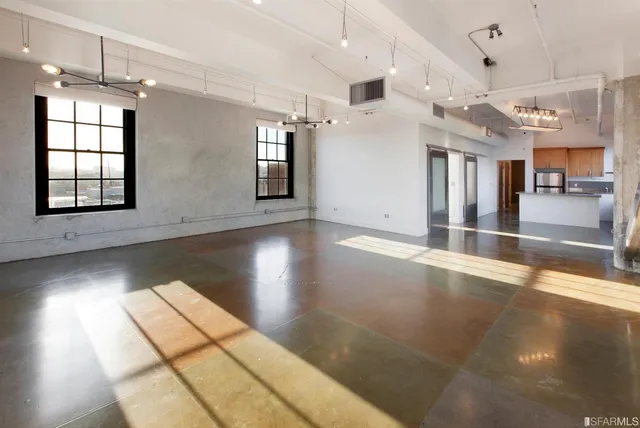a view of an empty room with chandelier fan and wooden floor