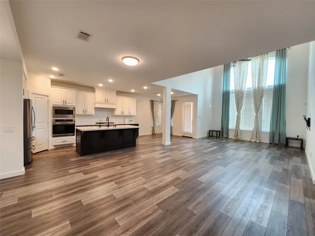 a view of kitchen with kitchen island wooden floor center island and stainless steel appliances