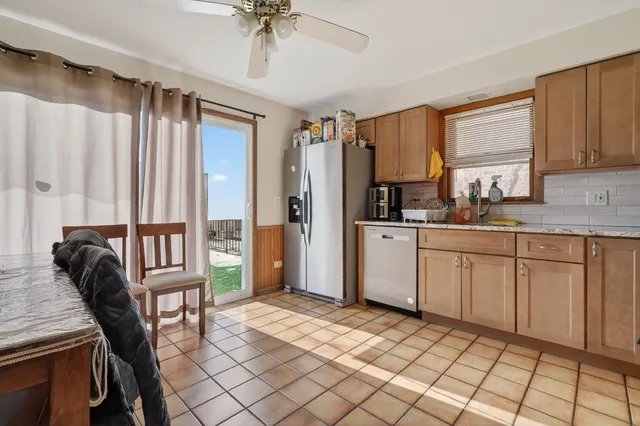 a kitchen with granite countertop a refrigerator a sink a stove and white cabinets