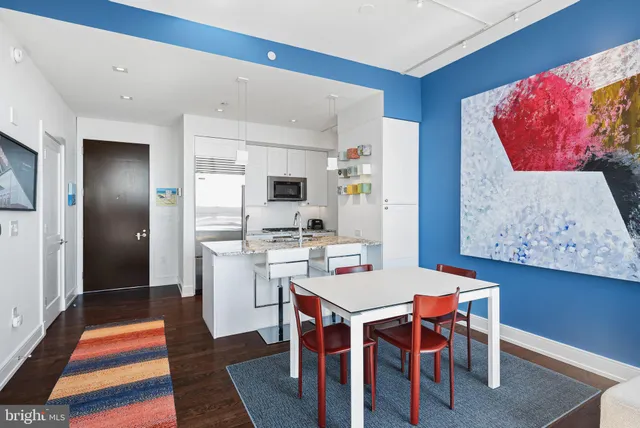 a open dining room with stainless steel appliances kitchen island granite countertop a dining table and chairs with wooden floor