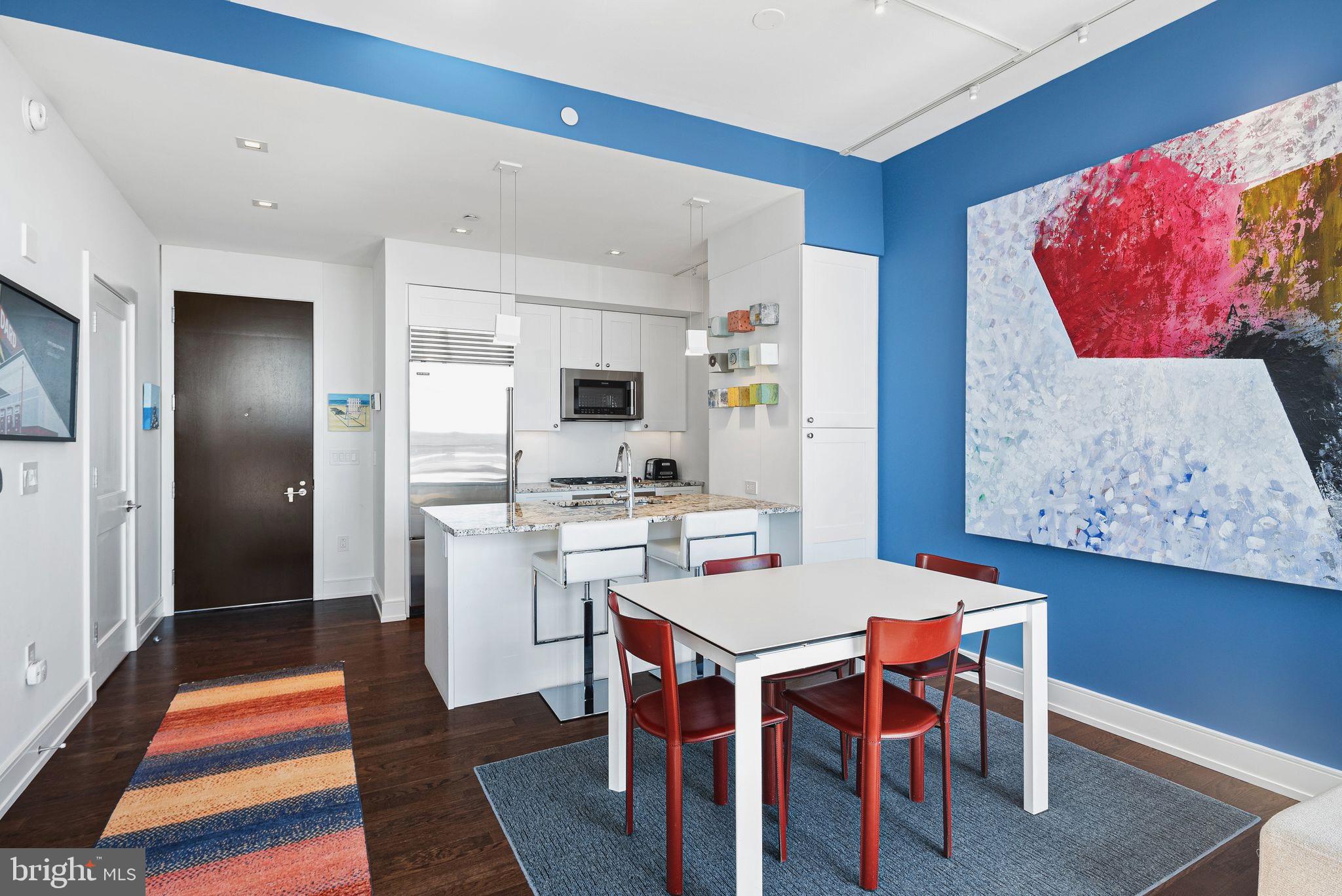 210 South 25th Street, Unit 905 Philadelphia, PA 19103 - Photo 6 of 28 a open dining room with stainless steel appliances kitchen island granite countertop a dining table and chairs with wooden floor