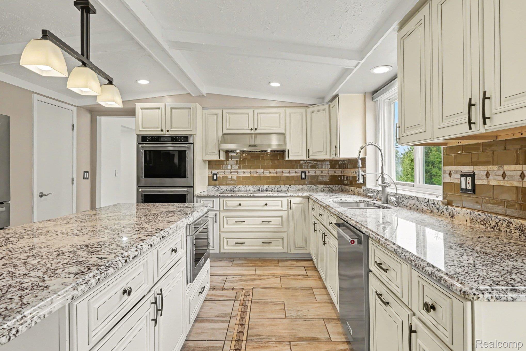 1941 Mapleridge Road Rochester, MI 48309 - Photo 16 of 55 Kitchen featuring backsplash, light stone counters, stainless steel appliances, pendant lighting, and lofted ceiling