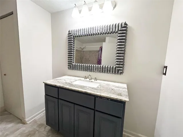 a bathroom with a granite countertop sink and mirror
