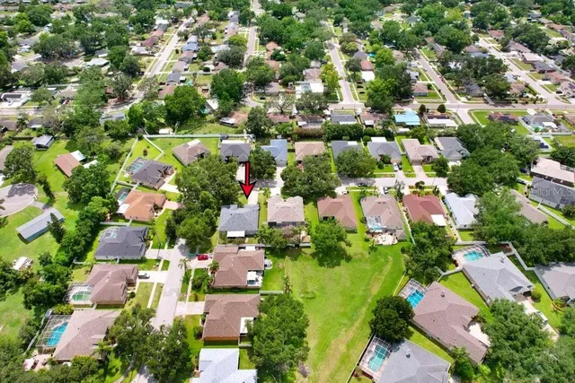 an aerial view of residential houses with outdoor space and trees all around